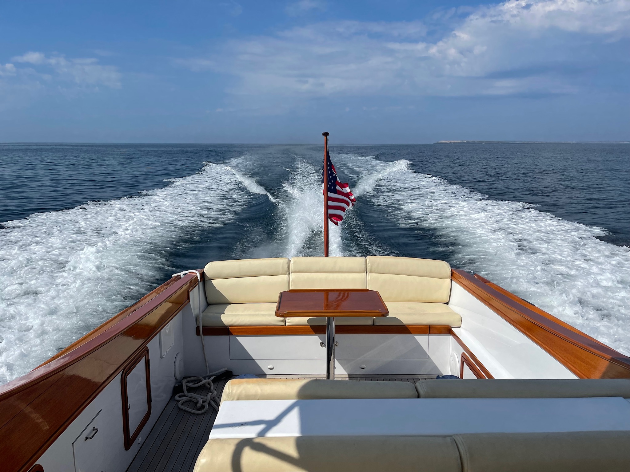 Boat stern with American flag and wake on open water